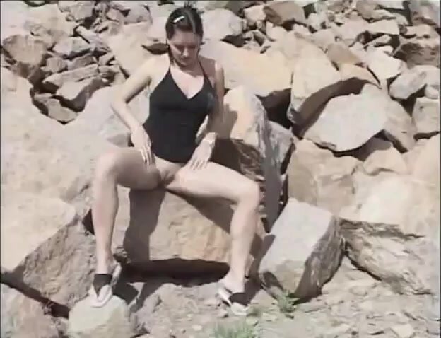 Cute girl peeing on rocks..