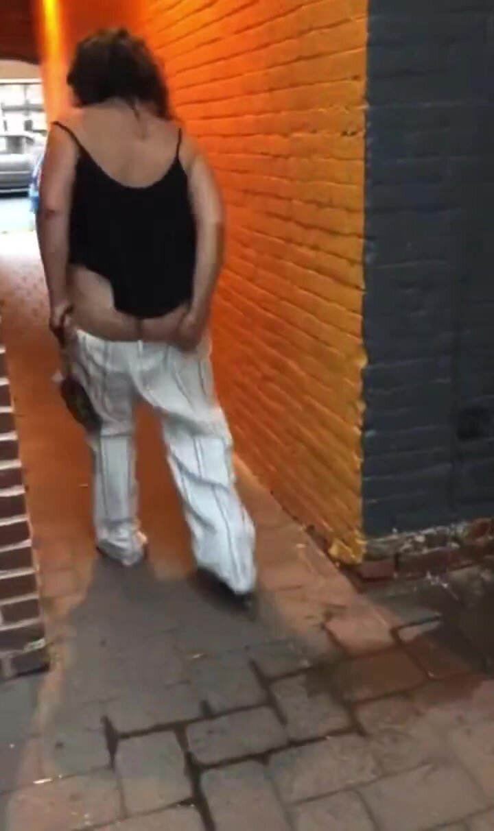 Catches the end of lady pissing on walkway by street