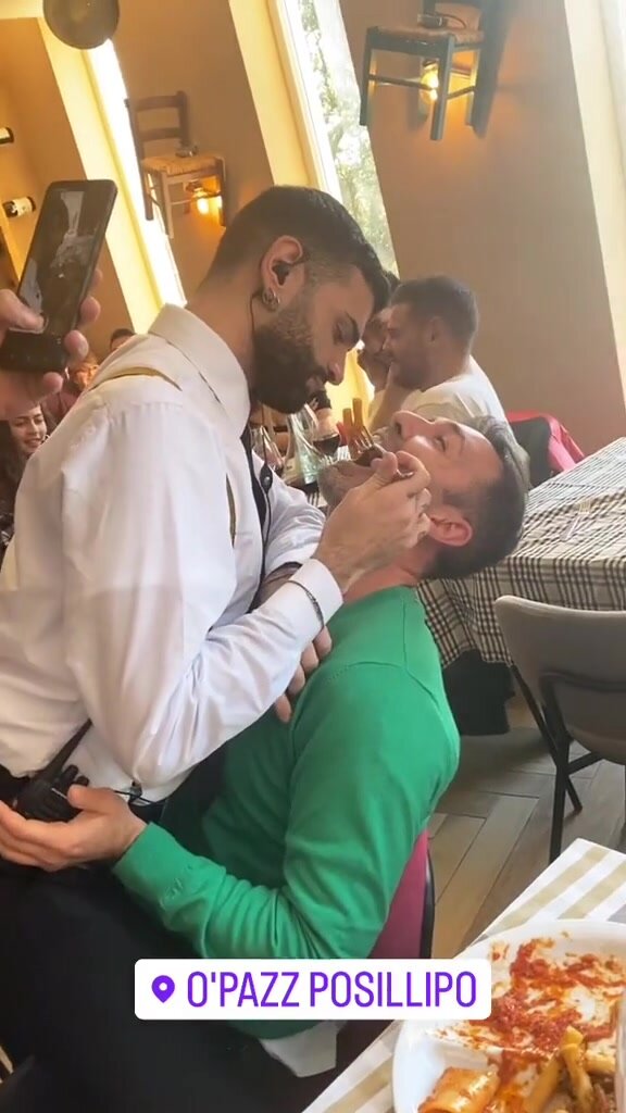 Hot gay waiter sits on straight guy's lap and feeds him