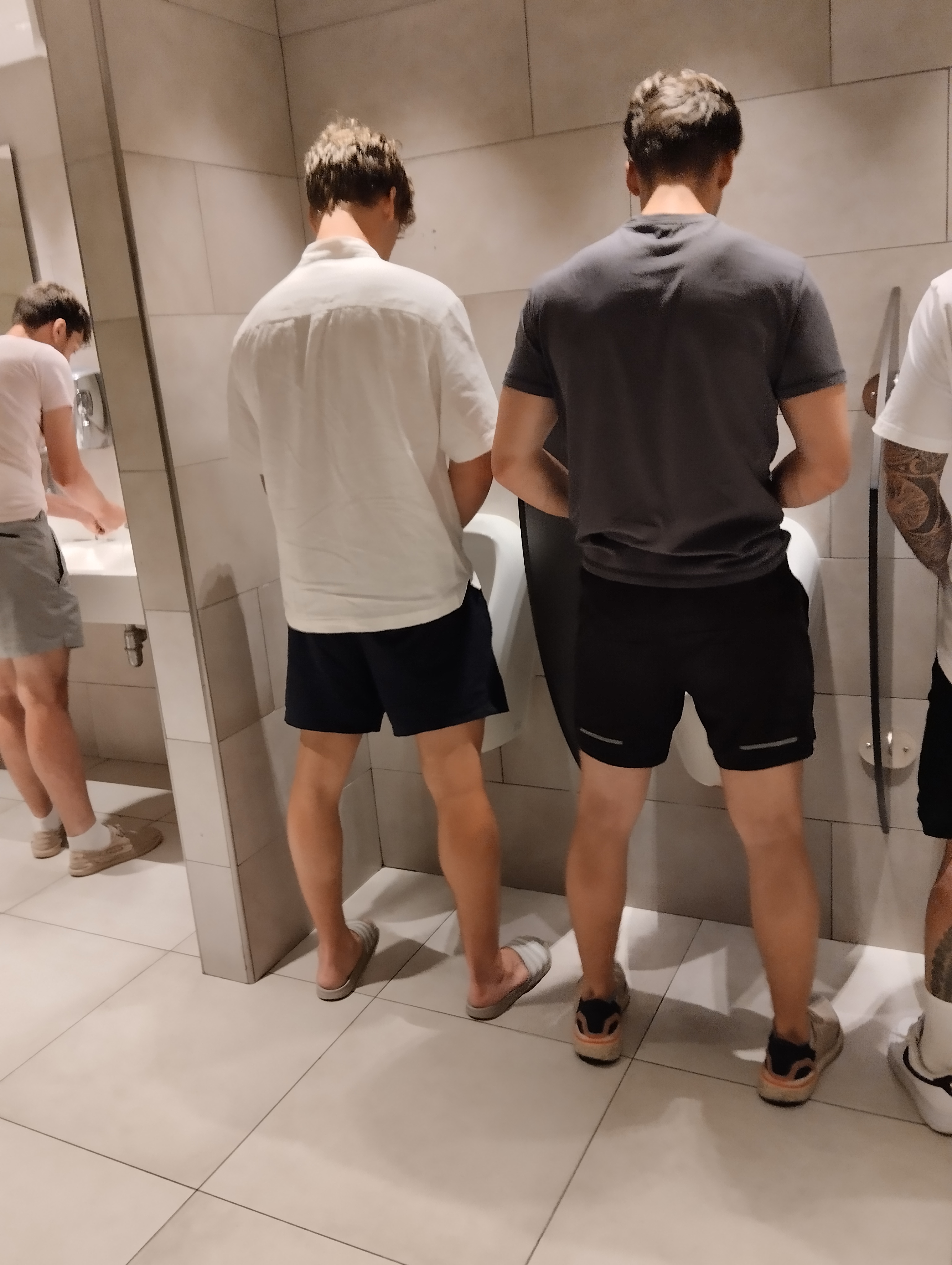 Two Norwegian brothers peeing at urinals in Italy