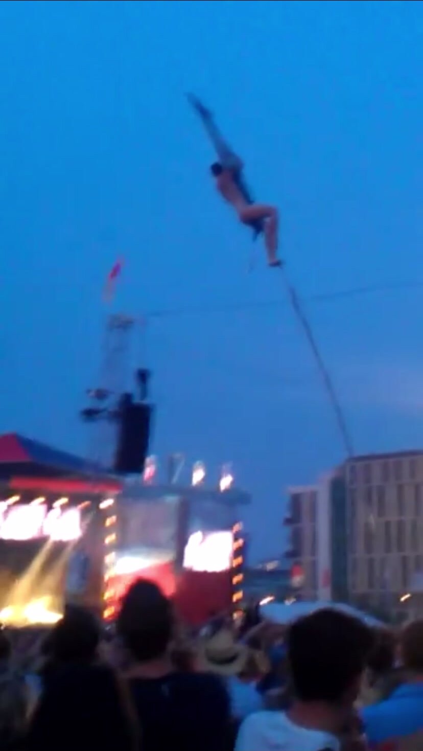Naked man climbs pole for cheering crowd