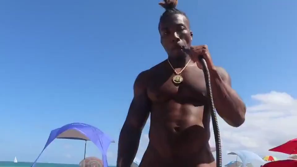 Nudist stud smokes on the beach