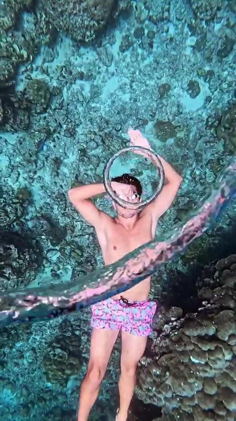 Shaved pits swimmer blowing air rings underwater in sea