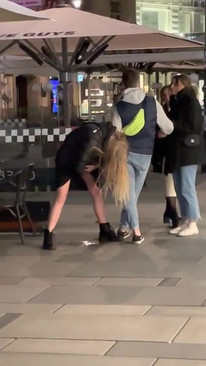 Male friend helps drunken,pissing lady keep her balance