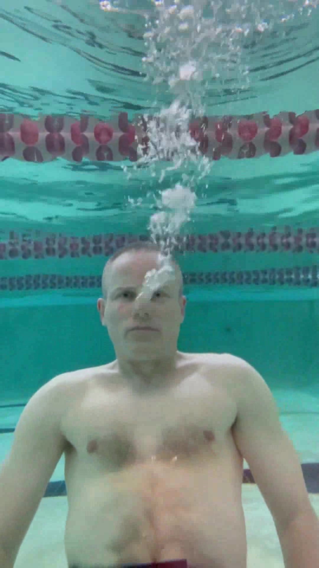 Barefaced guy blowing nose bubbles underwater
