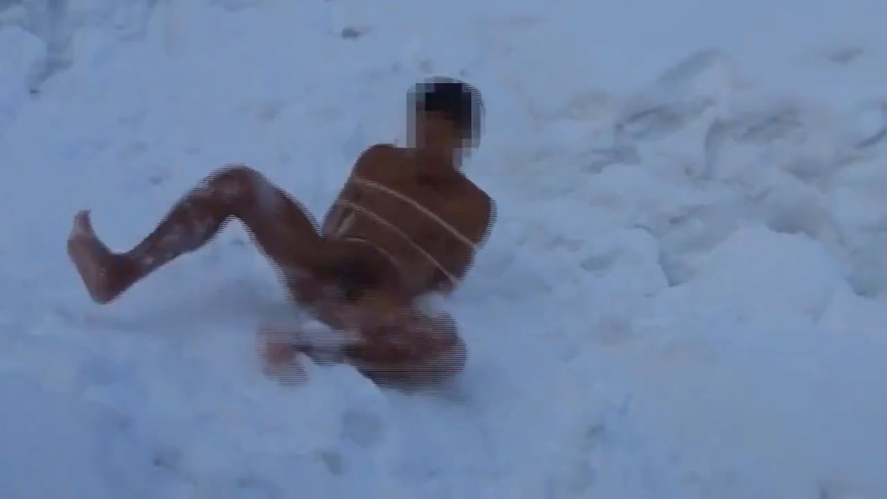 Naked man rolling down a snowy slope