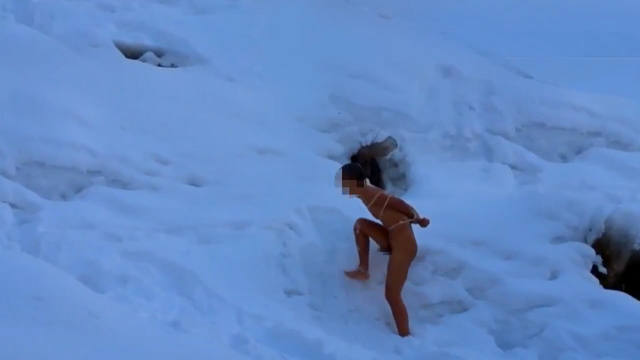 Naked man climbing a snowy slope